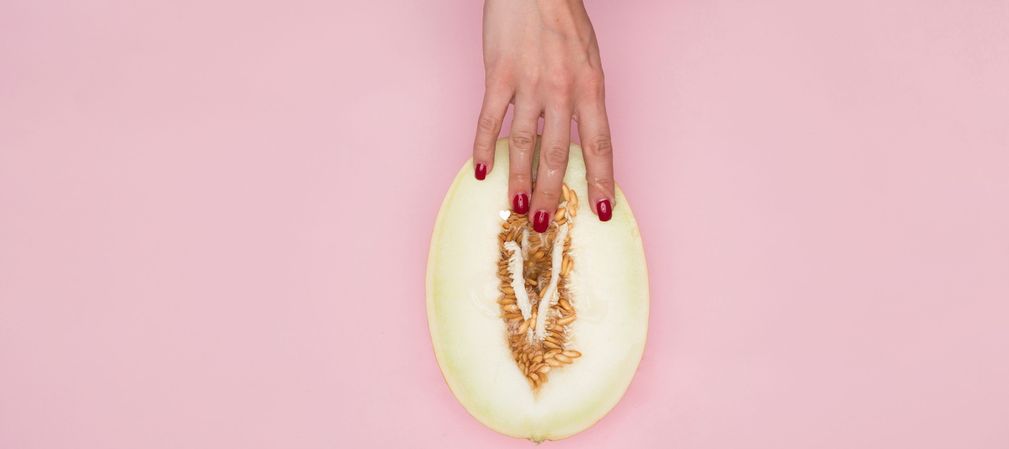 Hand einer Frau berührt die Kerne einer aufgeschnittenen Honigmelone